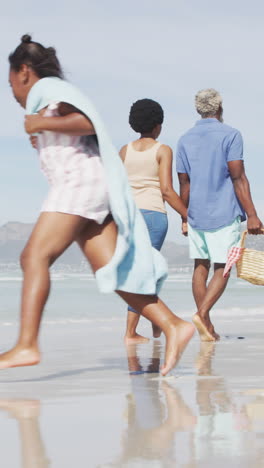 african american couple walking with children on sunny beach