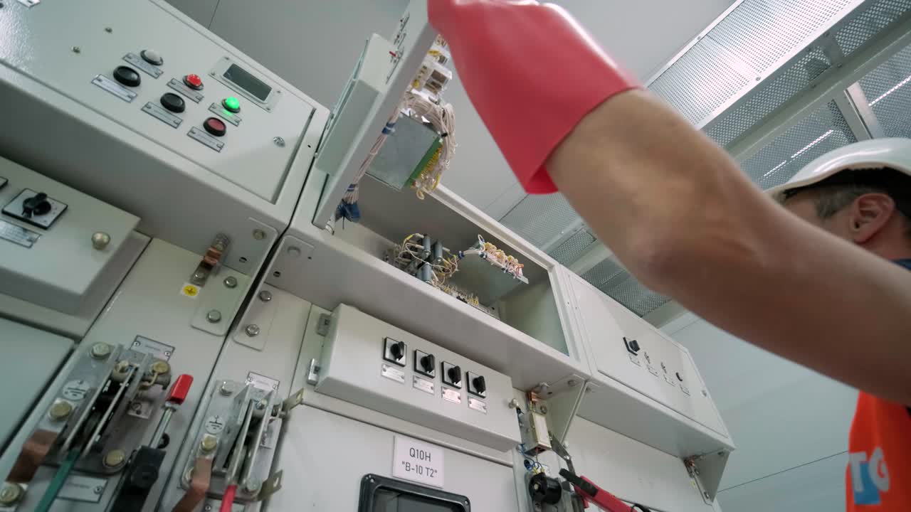 el ingeniero eléctrico que trabaja comprueba la tensión de corriente eléctrica y la sobrecarga en la parte delantera del gabinete del centro de carga o de la unidad de consumo para el mantenimiento en la sala principal del sistema de distribución de energía.