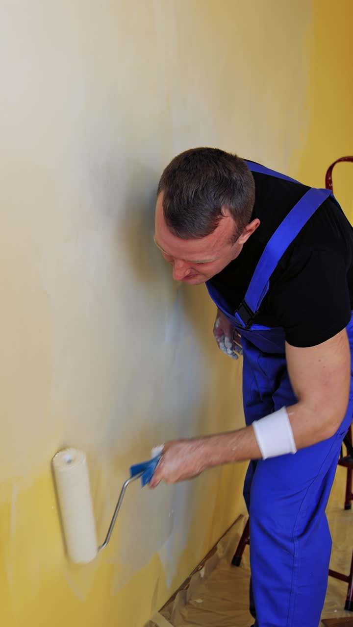 Man painting walls of room. Young male decorator painting wall in the empty room