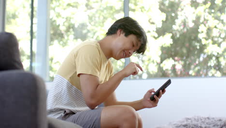 teenage asian boy enjoys a game on his phone at home