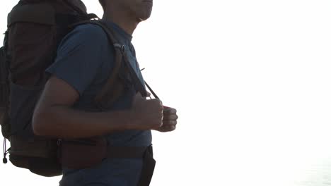 cropped shot of male backpacker standing at cliff