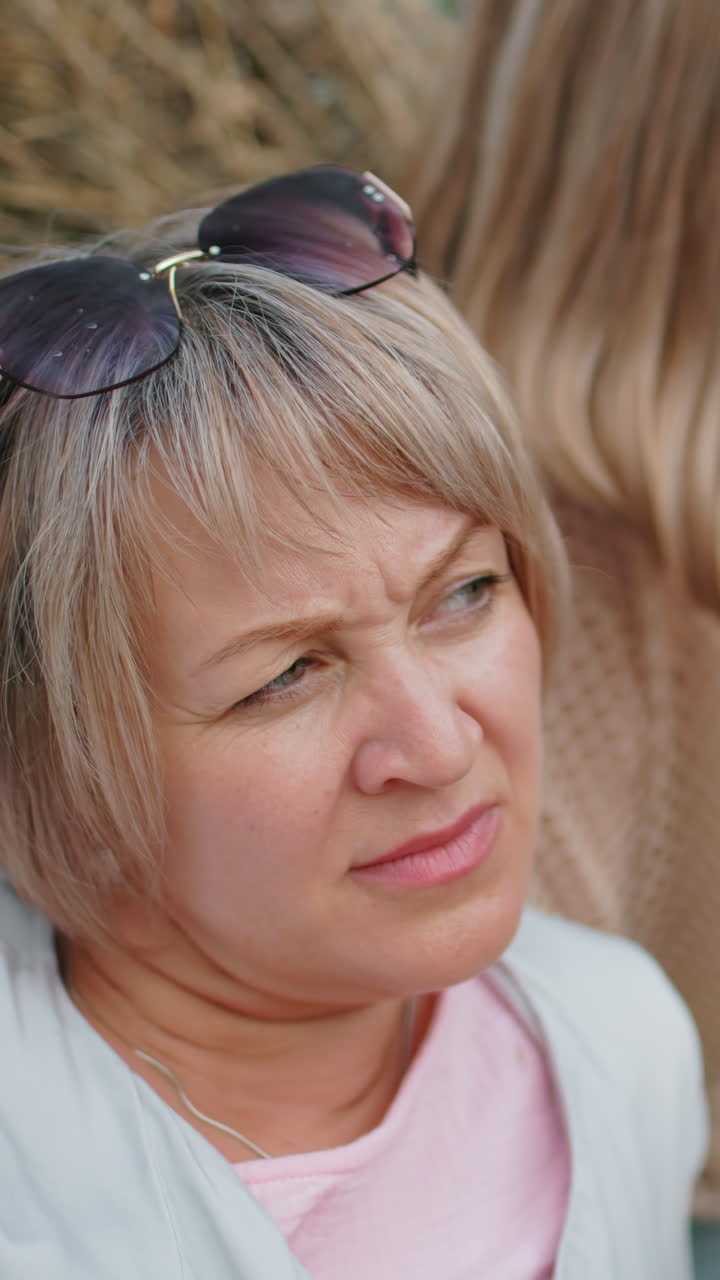 두 친구가 풀 근처에서 평화로운 야외 휴식을 즐기고, 머리에 선글라스를 착용하고, 평온한 시골 환경은 따뜻함, 평온함, 그리고 깊은 생각을 포착합니다.