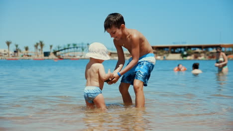 cute children splashing water at beach. adorable boys playing at seaside.