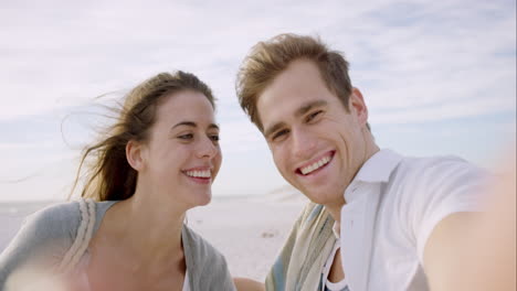 Feliz-Pareja-De-Mensajes-De-Video-En-La-Playa-Al-Atardecer-Usando-El-Teléfono-Sonriendo-Y-Girando-Disfrutando-De-La-Naturaleza-Y-El-Estilo-De-Vida-En-Vacaciones