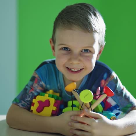 happy boy with toys. smiling little child with blue eyes holding many bright toys on the room background. happy childhood.
