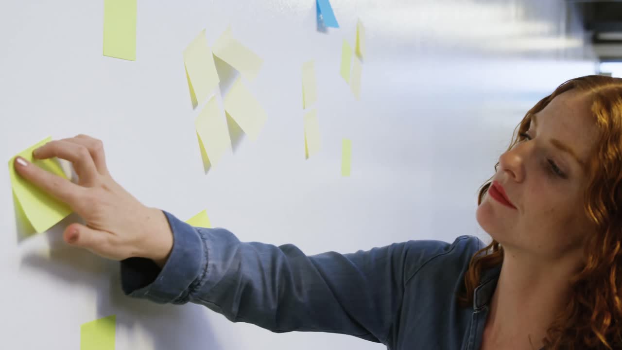 mujer de negocios leyendo notas adhesivas en la pizarra blanca 4k