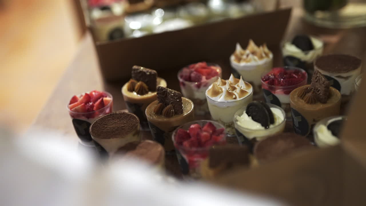 Fresh, individual dessert cups with toppings like fruits and cookies on a wooden table
