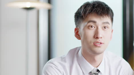 close-up of a young asian man in a shirt and tie indoors