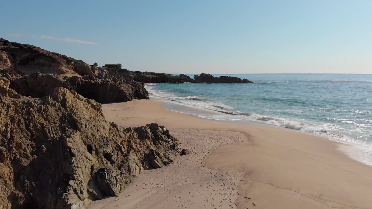 Praia rochosa na Califórnia com ondas quebrando na areia ensolarada