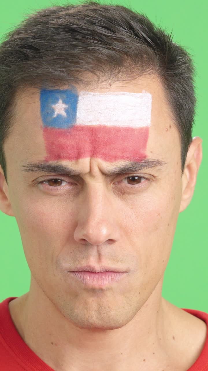 Serious man with a chilean flag painted on the face