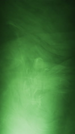 vertical video of green clouds of smoke moving with copy space on black background