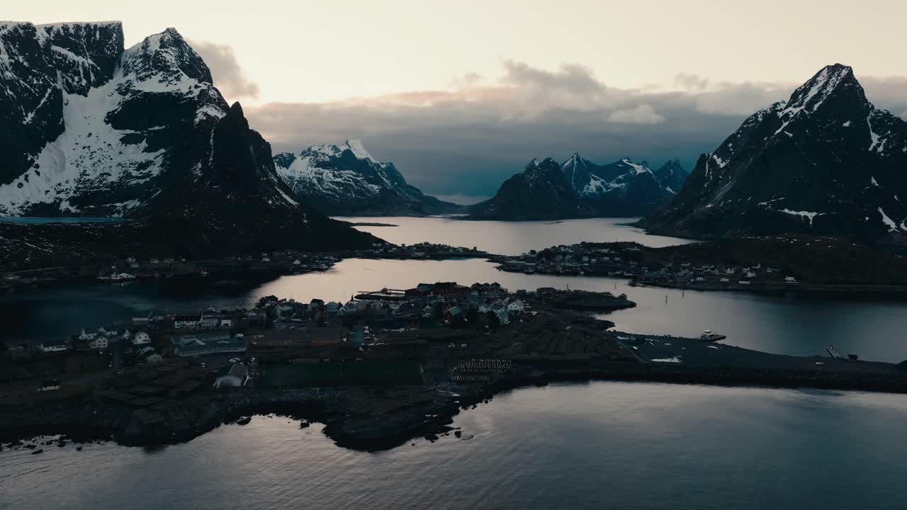 Vila Nórdica de Reine ao entardecer, cercada por fiorde e montanhas em Lofoten, Noruega. Vista aérea.