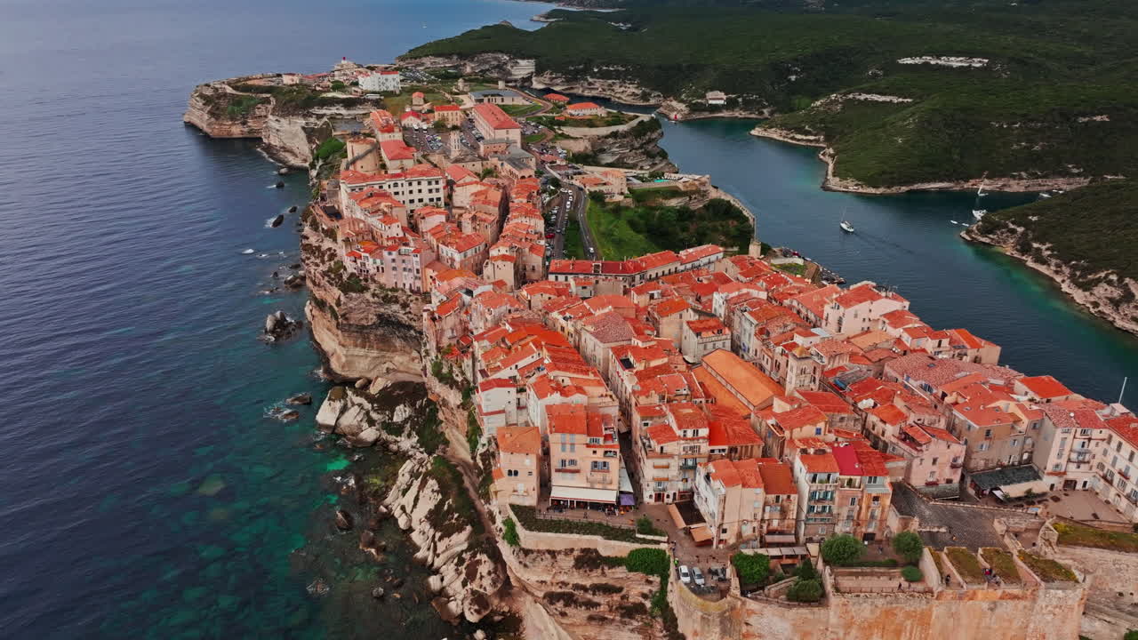 Aerial drone shot over the historic coastal town of Bonifacio in Corsica, France. High view of the rocky steep cliff and the turquoise sea. Ancient Citadel overlooking the rugged coastline