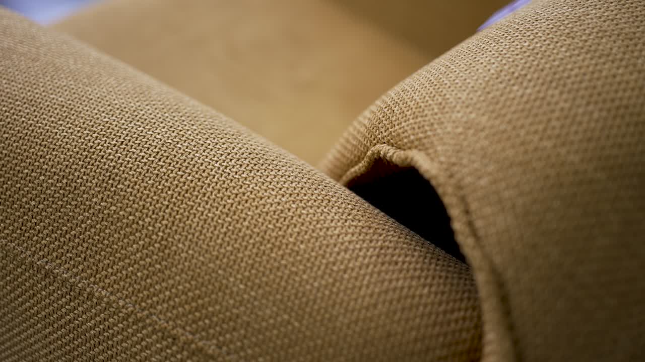 Observing the detailed texture and color of soft fabric on a comfortable chair in a warm, inviting space. The design enhances the cozy atmosphere of the room