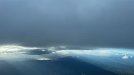 shot from a jet cockpit, pilot point of view, while flying bellow some grey clouds during climb