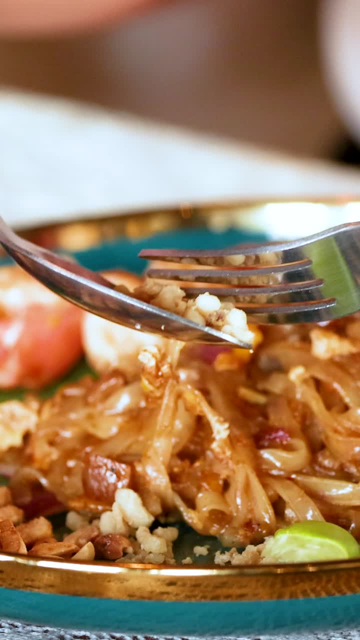 맛있는 새우 패드 태국을 가락으로 맛보고 있습니다.