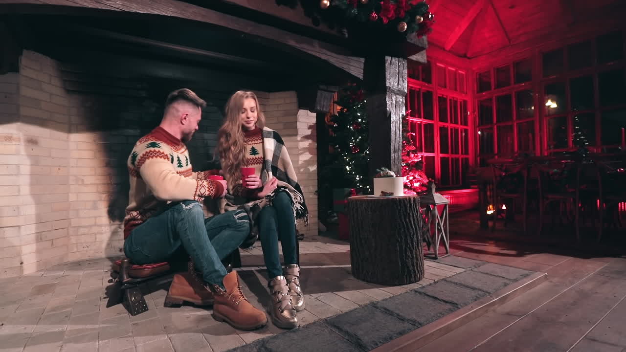 Couple of young people relax in a country house. Romantic couple sitting together at home with Christmas decorations. Pleasant vacation in winter.