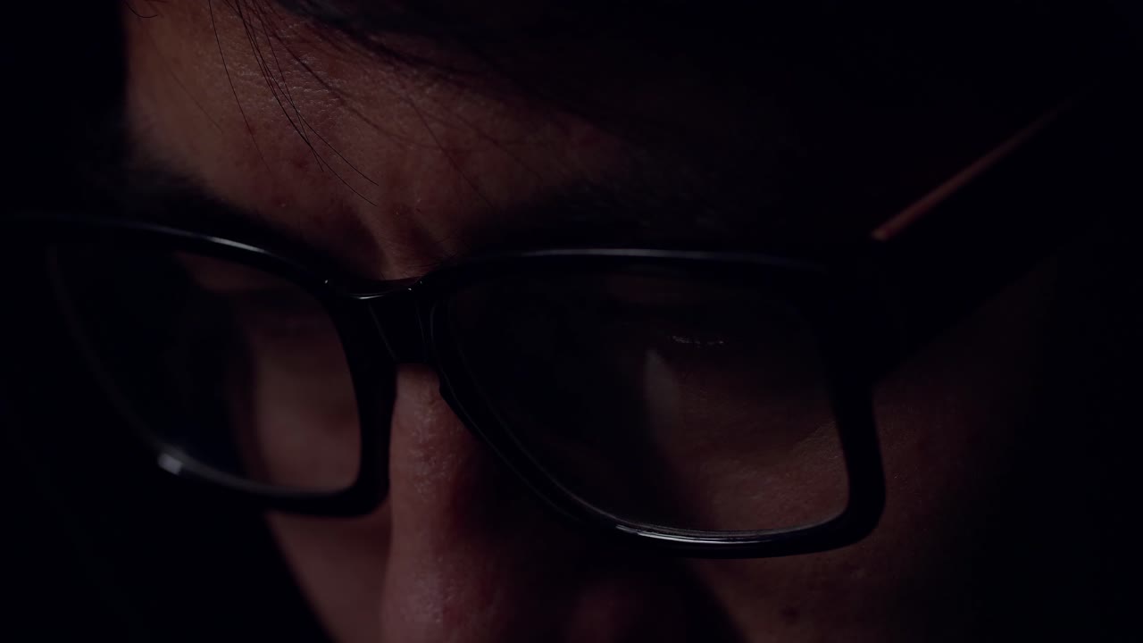 Close Up View Of Focused Man Wears Computer Glasses For Reducing Eye Strain Blurred Vision Looking At Pc Screen With Computer Reflection Using Internet, Reading, Watching, Working Online Late