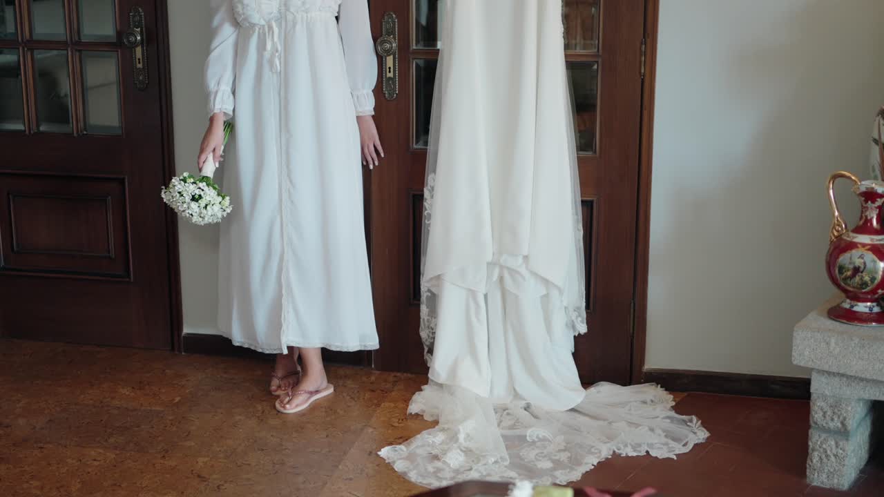 나무 문 에 매달린 웨딩 드레스  에 꽃받침 을 들고 있는 신부