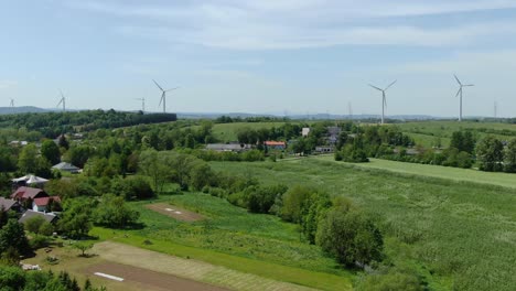 aerial dolly above small town in poland countryside and wind farm with turbines