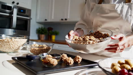 woman preparing granola and healthy snacks in kitchen