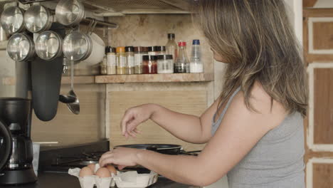 side view of japanese woman breaking eggs for omelet in kitchen