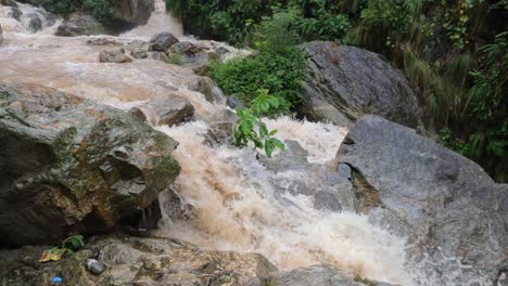 water raging over the rocks of a waterfalls in the hills of nepal during the rain from a typhoon