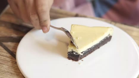 woman eating a piece of cheesecake with brownie crust