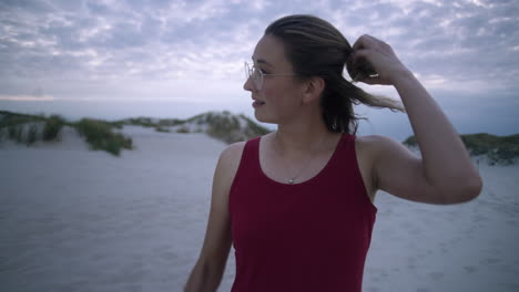 young woman opens her hair bun at a white sand beach