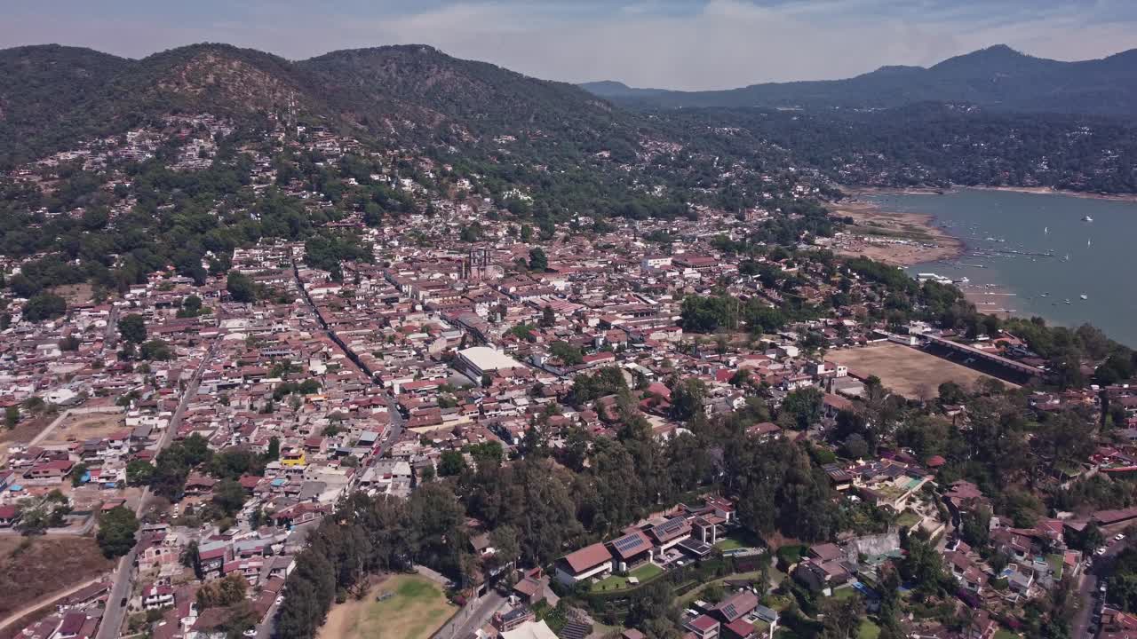 vista de avión no tripulado sobre la ciudad de valle de bravo en un domingo soleado, capturando las impresionantes vistas del lago y la iglesia principal, donde una rueda de la fortuna gira frente a la capilla