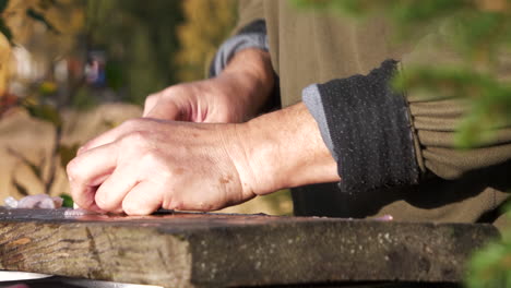el hombre limpia el pescado con un cuchillo en una tabla de madera al aire libre, un estilo de vida verde
