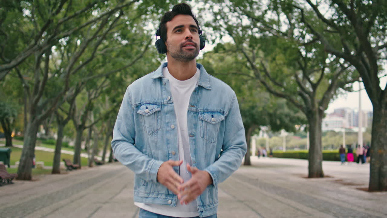 Walking guy enjoy music in wireless headphones at summer weekend outdoors.