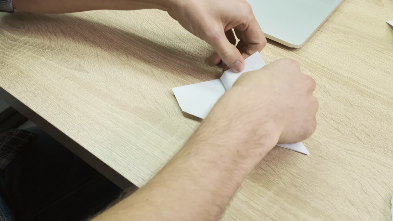 persona doblando un avión de papel