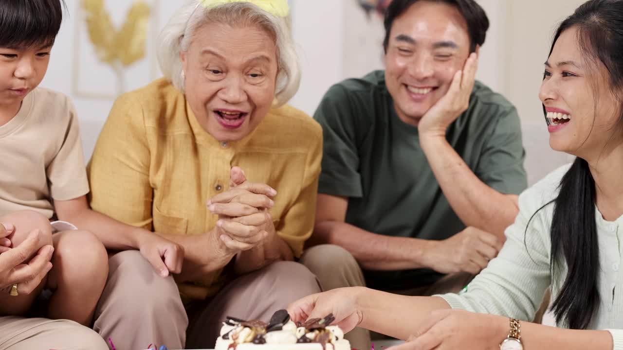 Elderly Asian family celebrates birthday with cake, laughter, and togetherness in a cozy home
