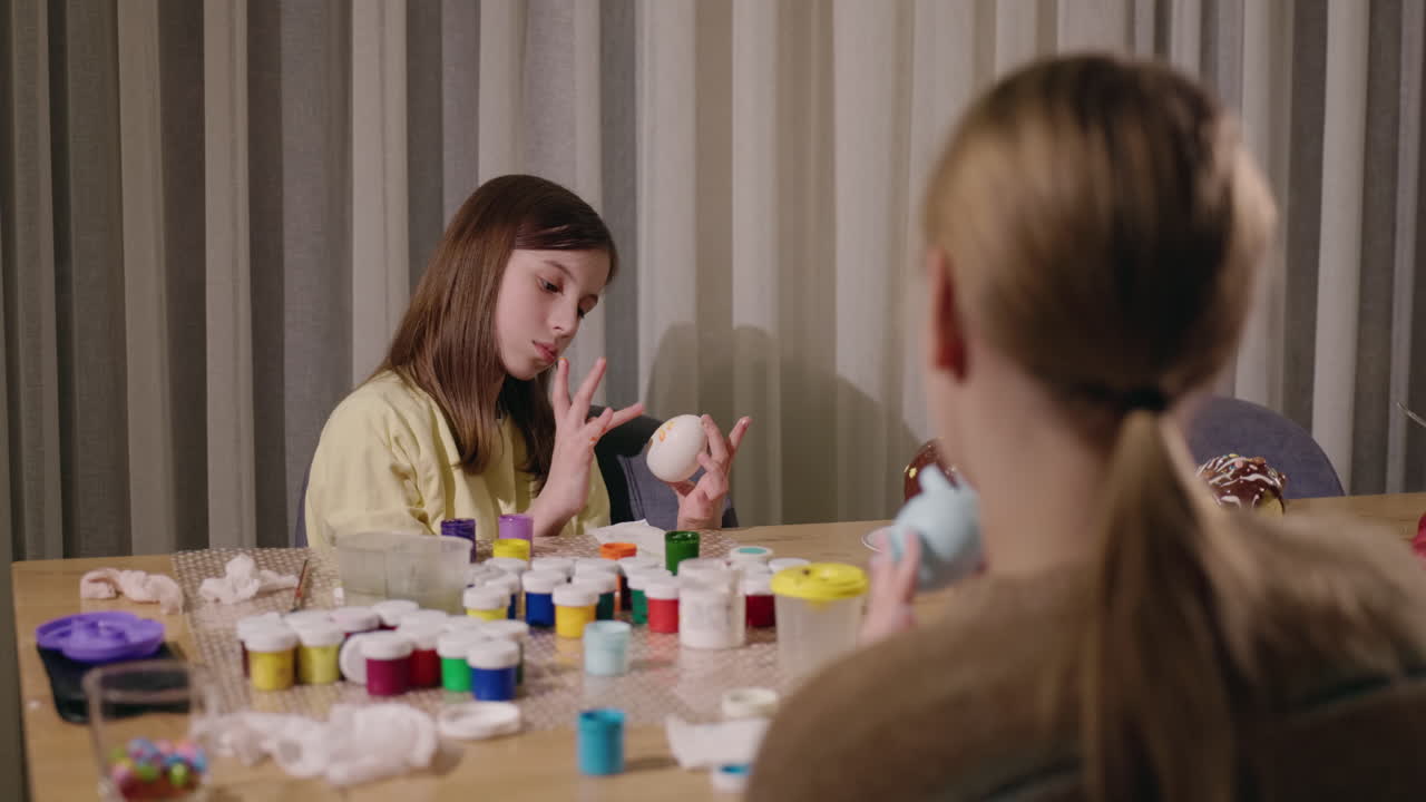 자매들이 집에서 부활절 달을 칠하고 있습니다.