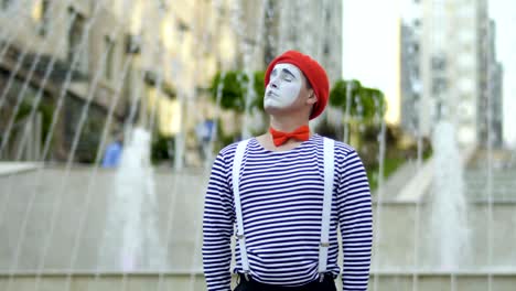 funny man mime in red beret and stripped shirt singing at fountains background