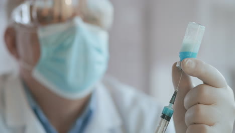 el médico dibuja la vacuna en el frasco de la jeringa para la inyección de la ampolla de coronavirus de covid-19. fotografía de cerca de una enfermera o médico irreconocible con guantes llenando la jeringa de la ampulla con vacuna contra covid-19. imágenes de alta calidad en 4k