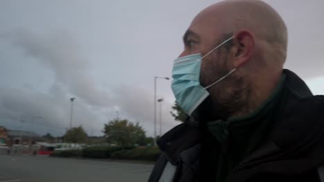 male in workplace wearing uniform and ppe face mask against corona virus walking car park