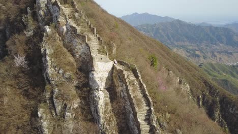 Female-photographer-climbs-steep,-wild-section-of-Great-Wall-of-China