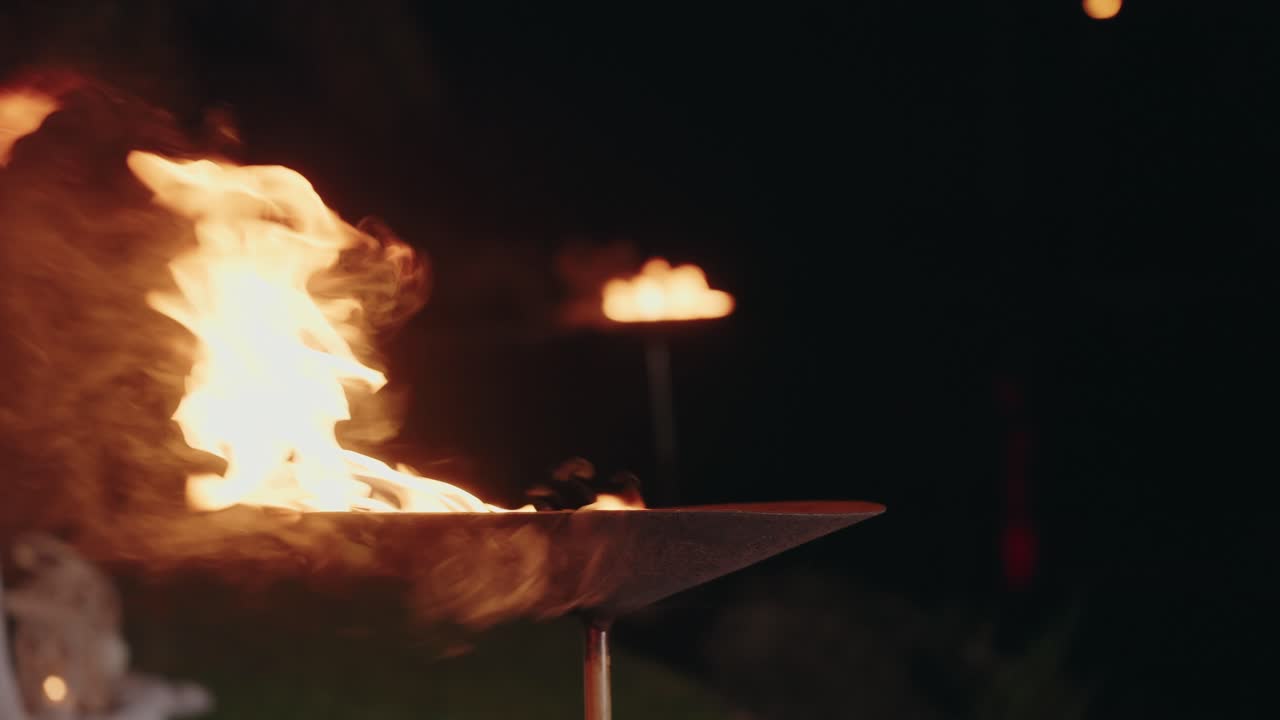 Close up of fire torch burning in metal bowl against dark night background