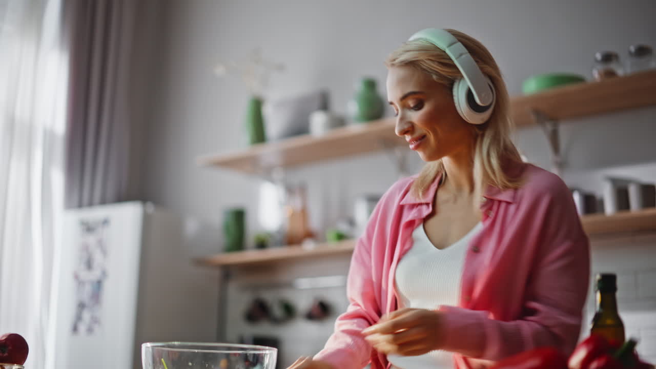 Chef hands pouring oil making salad at kitchen closeup. Girl listening music