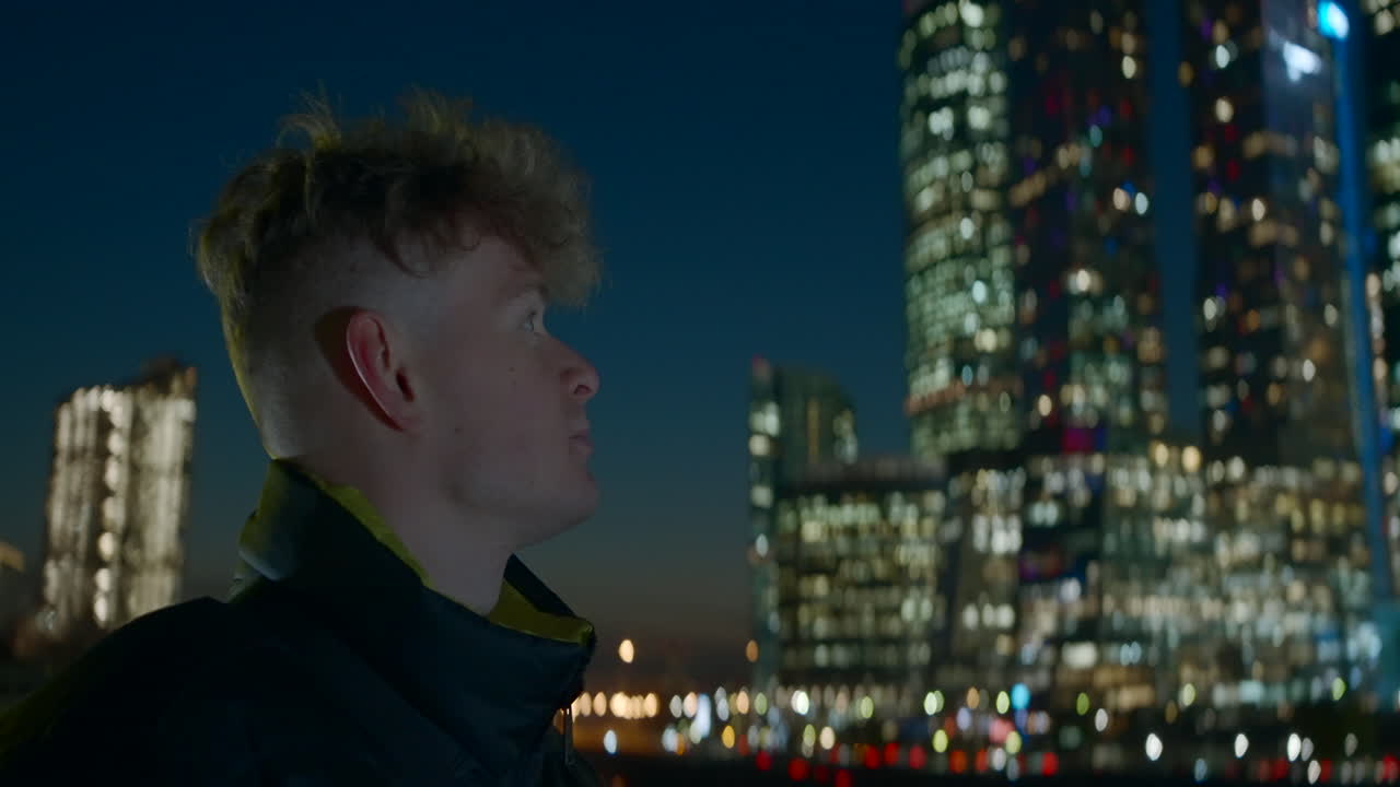 Man Looking at Night City Skyline
