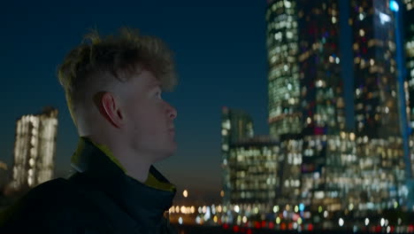 man looking at night city skyline