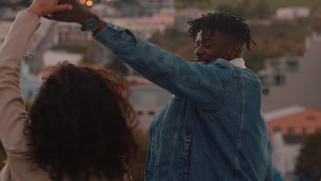 happy-multiracial-couple-dancing-having-fun-enjoying-rooftop-view-of-city-sharing-connection-friends-drinking-alcohol-hanging-out-on-weekend