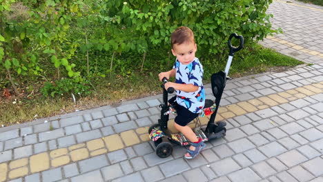 joyful caucasian toddler riding a bike by the paved road. baby has active time outdoors in summer.