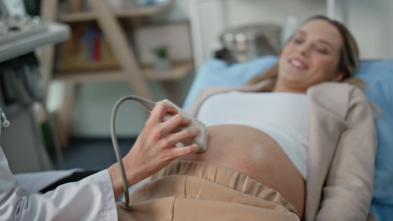 Medico che controlla il monitor dell'ecografia in clinica in primo piano. Donna incinta sorridente.