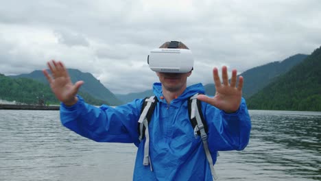 man using vr headset in a beautiful mountain landscape near a lake.