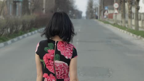 joven atractiva en un vestido con flores se vuelve a la cámara y sonríe