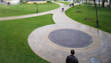 man walking in a park with circular paved paths