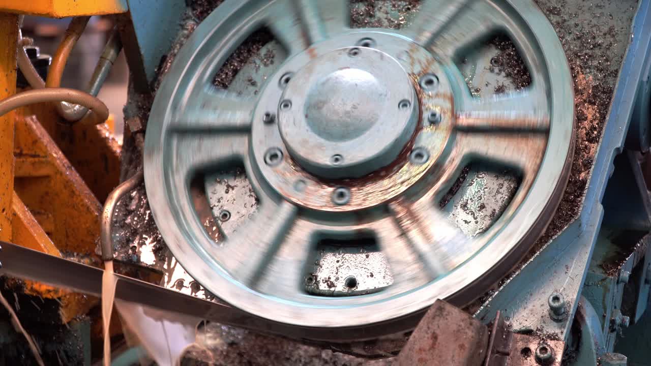 sierra de banda industrial, corte de tubos metálicos, líquido de enfriamiento en escena amarilla, herramientas industriales